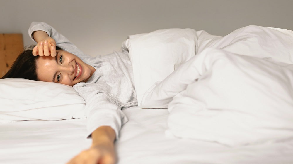 Frau liegt im Bett mit Kissen und Decke